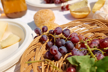 Summer beach picnic. Appetizers, fresh fruit, grape, yellow melon, bread, cheese and wine on white tablecloth outdoors at seaside at the beach.