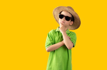 Boy on vacation wearing sunglasses wearing green t-shirt hat over isolated yellow background with...