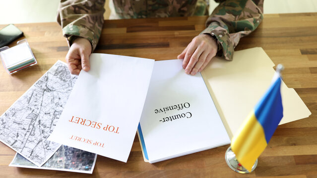 Military man holding in hands secret plans of Ukrainian counteroffensive operation - Powered by Adobe