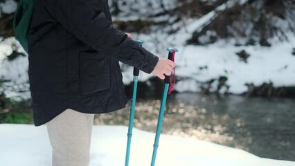 Middle aged woman travels with trekking sticks in the woods