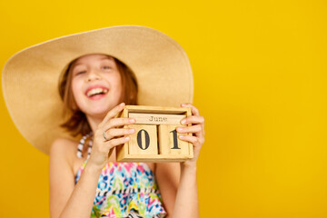 Child teenager girl in swimsuit and straw hat hold in hand wooden calendar