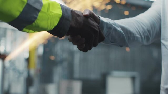 Two workers of the enterprise shake hands during the work process. The two uniformed engineers made a deal and shook hands.