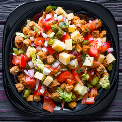 Salad in a black plate on a black wooden background