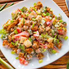 fresh vegetable salad in a white plate with green onion and tomato on a table next to the cutlery
