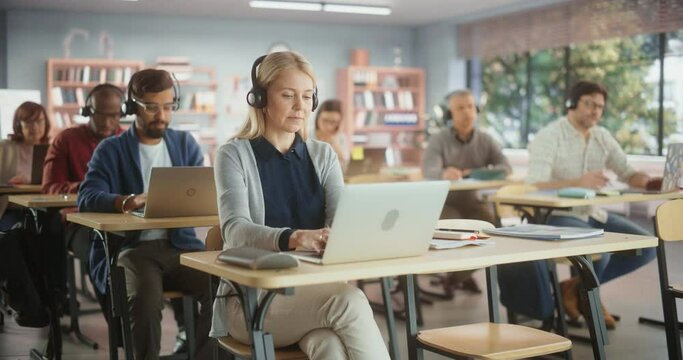 Multiethnic Women and Men of Different Age Acquiring New Academic Skills in Classroom. Diverse Mature Students Doing an Audio Language Exam, Listening to Assignment in Headphones