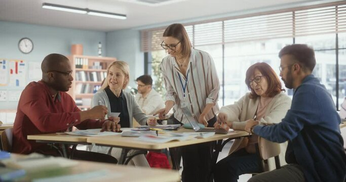 Grown Up Men and Women Working in Groups for an Assignment in Specialty Development Center. Adult Classmates Working on a Team Assignment, Young Female Teacher Explaining the Exercise Goals
