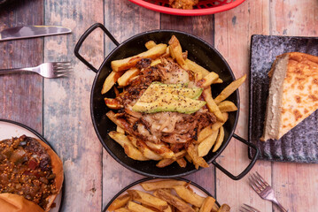 A few plates of 3 Latin fast food with shredded meat on chips with cheese and avocado