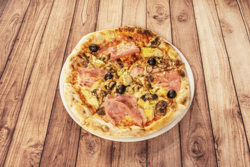 Whimsical Italian gastronomy pizza prepared with mozzarella cheese, oven-roasted Italian ham, artichokes,