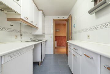 Kitchen furnished with white furniture and countertops of the same color and wooden details