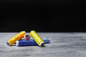 A few spools of unused colored thread on a gray surface
