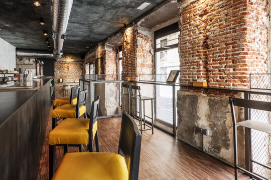 A local bar counter with high armchairs with yellow seats, industrial parquet floors