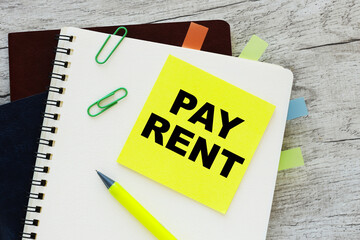 Pay Rent written on yellow sticker wooden background