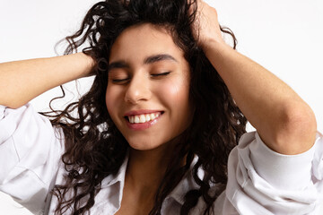 A happy young woman with black curly hair and a sweet white-toothed smile
