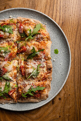 Juicy Roman pizza with shrimps, arugula, cherry tomatoes, sprinkled with parmesan close-up