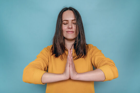 Woman with dark straight hair holds arms folded in front of chest. Meditation. Closed eyes.