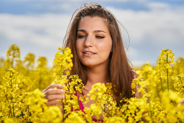 Beautiful woman with blue eyes in a canola field