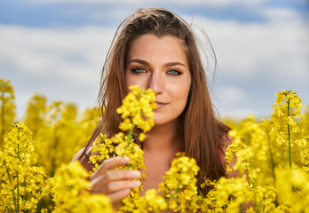 Beautiful woman with blue eyes in a canola field