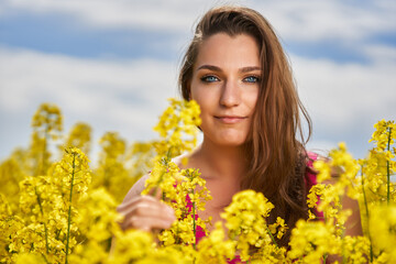 Beautiful woman with blue eyes in a canola field