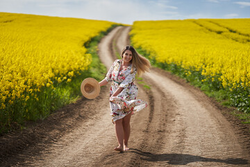 Romantic latino woman barefoot on a road in canola field