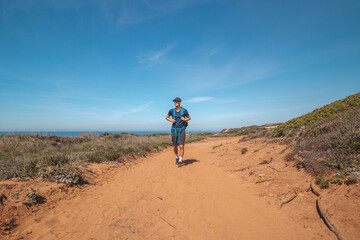 Explorer and hiker walk across the sandy terrain towards his destination in the Odemira region, western Portugal. Wandering along the Fisherman Trail, Rota Vicentina