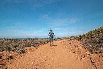 Explorer and hiker walk across the sandy terrain towards his destination in the Odemira region, western Portugal. Wandering along the Fisherman Trail, Rota Vicentina