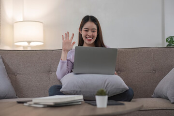 Woman having video call on her laptop at home. Smiling girl smile to family or friends