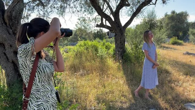 Girl photographer shoots a woman in an olive grove near a tree