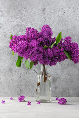 Lilac flowers bouquet in vase on gray background. Still life. Wedding or Mothers day card. Vertical orientation