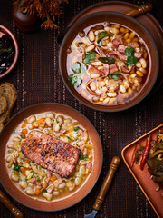 top view of two brown plates of bean soup on a brown tablecloth