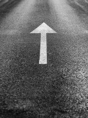 White arrow straight ahead direction of movement on dark asphalt, direction arrow sign for parking....