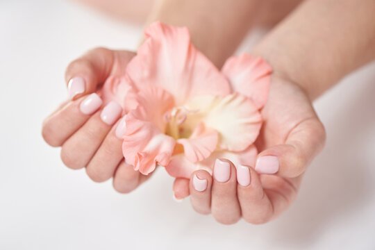 Gentle manicure of natural color and gladiolus flower. The concept of femininity