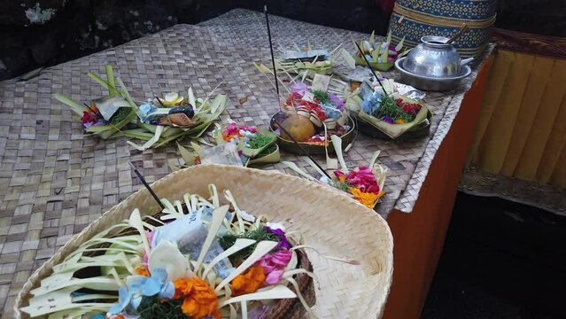 Sage and Religious Vessels Displayed in Bali Temple Ceremony, Colorful Flowers and Coconut Baskets for Praying Ritual