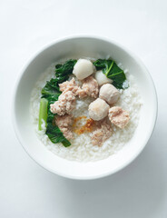 Rice porridge with mined pork, fish ball, meat ball and vegetable isolated with white background. Top view