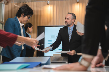 Professional team of focused business executives analyzing company annual financial paper report to balance together at office. Business market with modern office and tax document concept