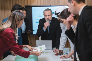 Professional team of focused business executives analyzing company annual financial paper report to balance together at office. Business market with modern office and tax document concept