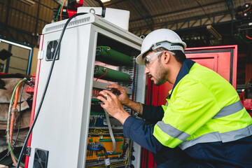 Production engineers in safety wear are assisting adjusting and maintaining CNC or factory machine,...