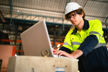 Professional engineer holding robot controller checking and repairing automatic robotic machine at...
