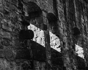 photograph of an old castle wall with shutters through which sunlight falls in black and white colors