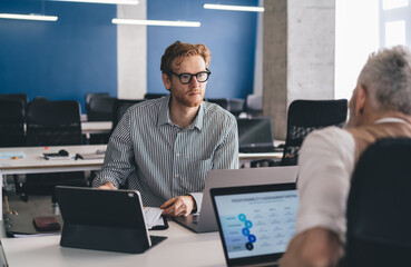 Young redhead employee collaborating on project with colleague