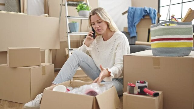 Young blonde woman talking on smartphone looking upset at new home