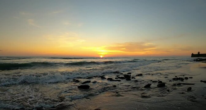 Sunset over the rocky beach with sea waves