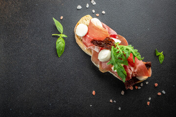 Spanish Tapas with cured Slices of jamon iberico ham with basil on a dark background. banner, menu,...