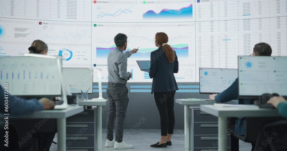 Poster zoom out back view of indian man and hispanic woman discussing financial reports on digital screen i