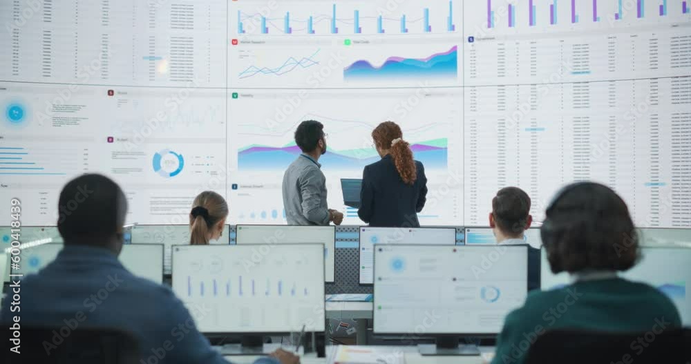 Poster Wide Shot of Diverse Male And Female Data Analysts Discussing Graphs And Reports On Big Digital Screen In Monitoring Office. Multiethnic Employees Working On Desktop Computers for AI Company.