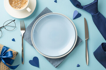 Elevate your Father's Day celebration with this stylish table setting. Top view flat lay of plates, cutlery, napkin, tie, and more on pastel blue backdrop, empty space for your custom message or ad