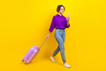 Full length photo of pretty sweet lady wear violet shirt walking check in flight modern device isolated yellow color background