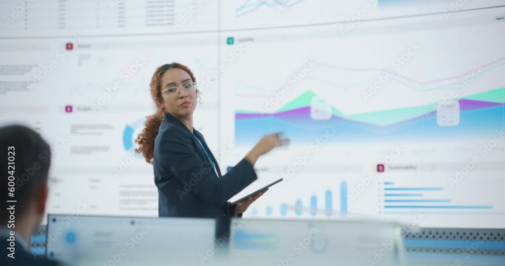 Poster Hispanic Female Senior Data Scientist Reviewing Reports Of Risk Management Department On Big Digital Screen In Monitoring Room. Diverse Consulting Company Employees Working Behind Desktop Computers.
