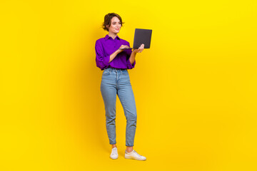 Full size photo of pretty young girl hold netbook device wear trendy violet smart casual outfit isolated on yellow color background