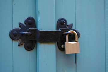 Antique metal lock with a decorative massive overlay on a blue wooden door. Close-up. Security.
