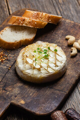 Baked Camembert cheese on a wooden board. Baguette